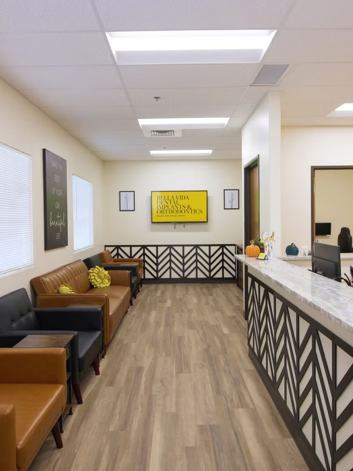 The image shows an interior space with a modern design, featuring a waiting area with seating, a reception desk, and decorative elements such as wall art and a sign that reads  The Wellness Center.