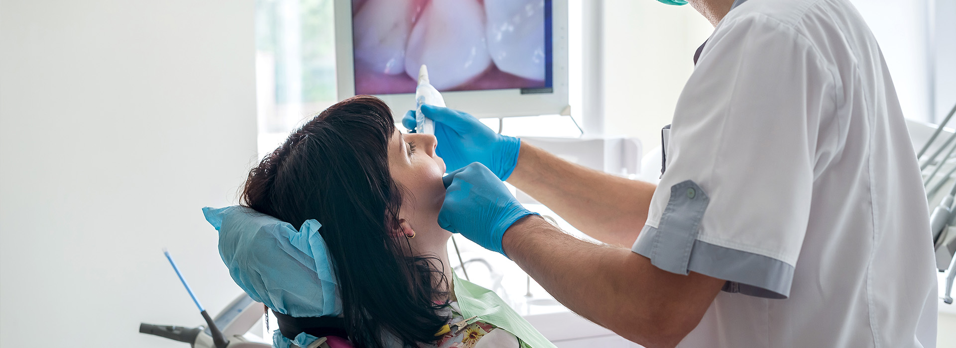 A dental professional adjusting a patient s mouth with their hands, using dental tools, while seated in an office chair.