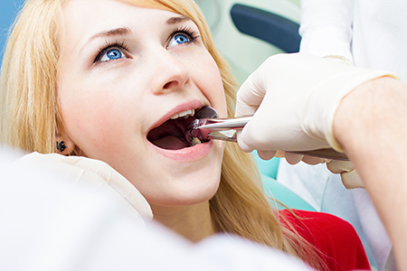 A woman receiving dental care with a dental hygienist performing the procedure.