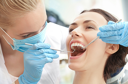 A dental hygienist performing a teeth cleaning procedure on a patient s mouth.