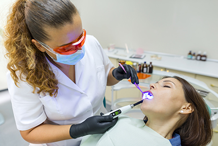A dental hygienist providing teeth cleaning service using an ultrasonic scaler.